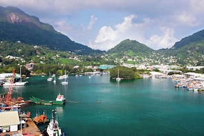 A coastal town with a marina, boats, and a mountainous backdrop.