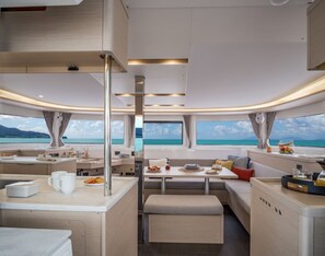 A modern interior with a kitchen, dining area, and seating by large windows overlooking a scenic view.