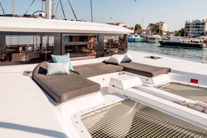 A yacht with a modern lounge area featuring cushioned seating and a glass enclosure.