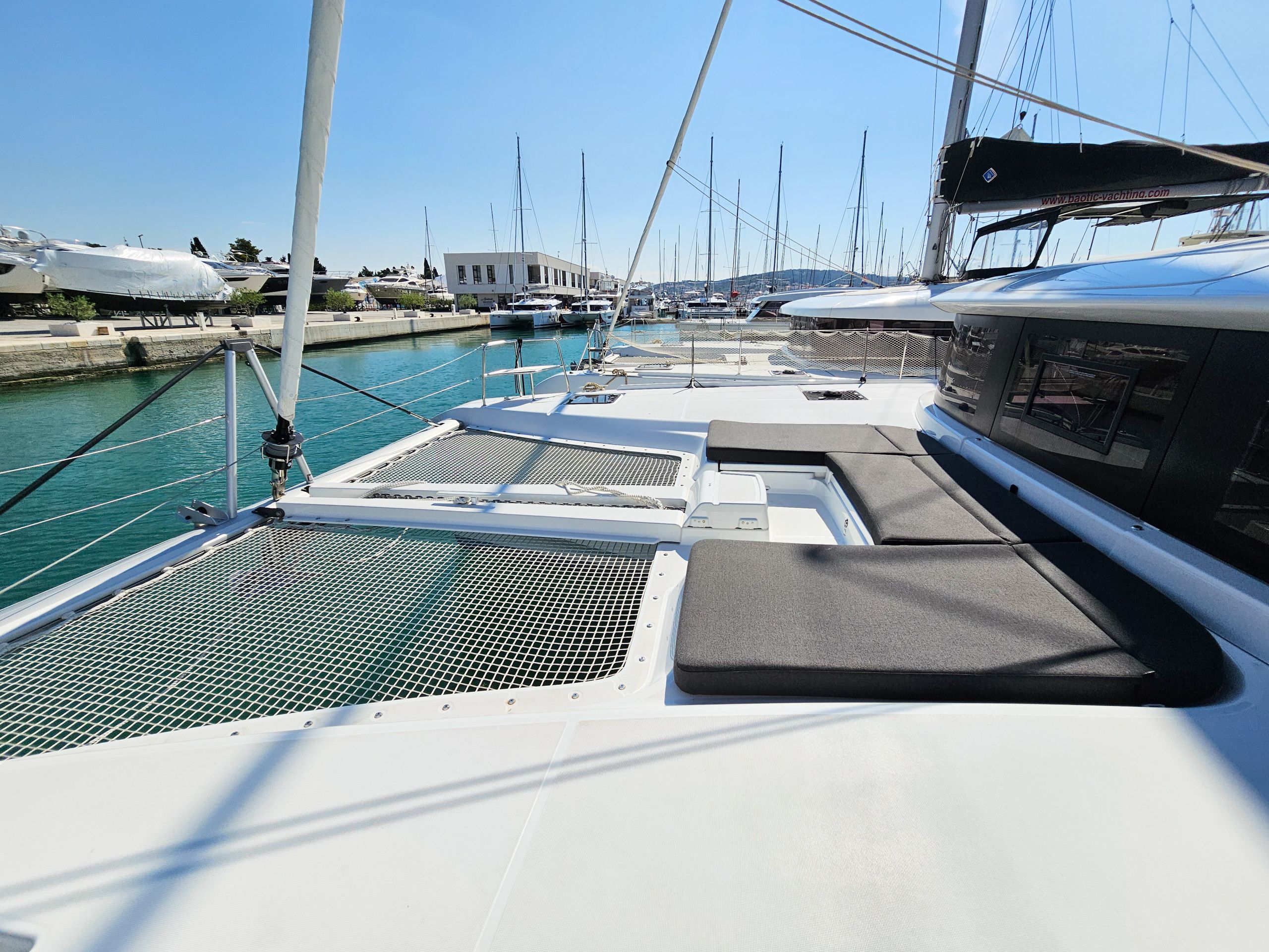 A marina with boats docked, a white building in the background, and a clear sky.