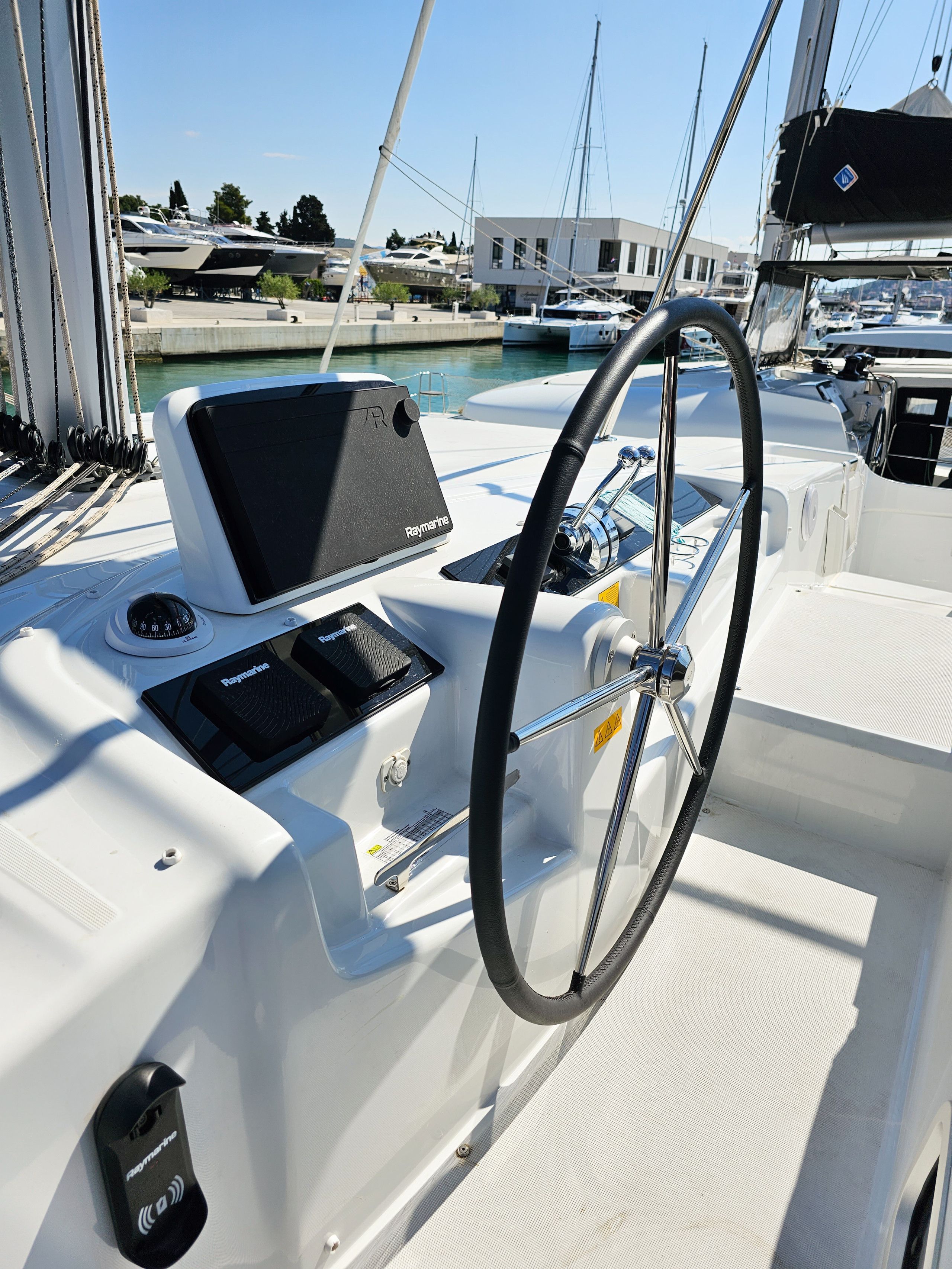 Un poste de commande de bateau équipé d’un volant, d’un système de navigation Raymarine et d’une prise d’eau.