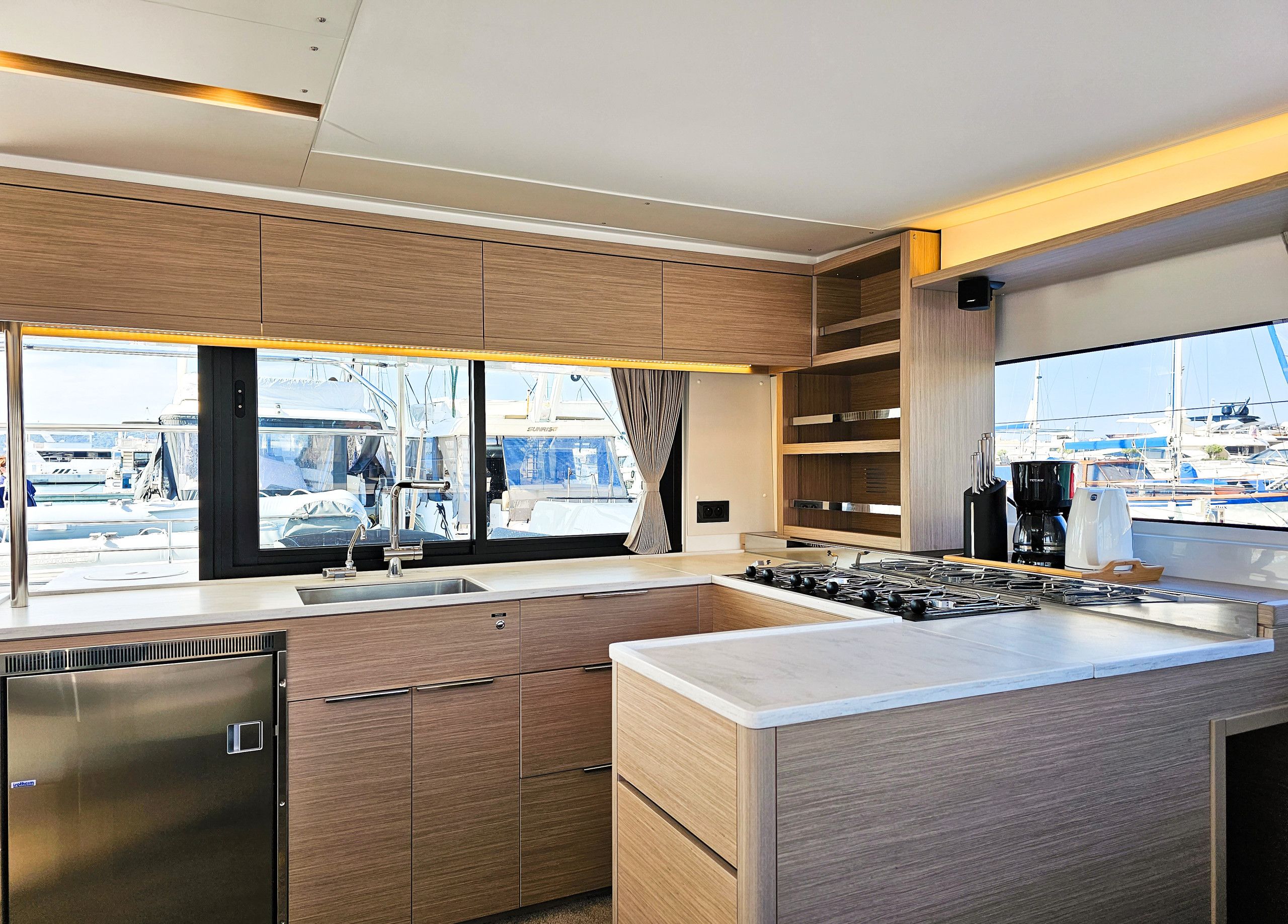 A modern kitchen with a large window, stainless steel appliances, and wooden cabinetry.