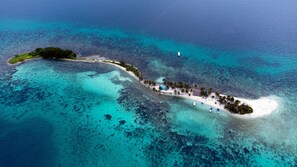 Ein Luftbild einer tropischen Insel mit Strand, Booten und klarem, blauem Wasser.