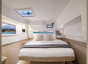 A modern yacht bedroom with a bed, skylight, and a view of the sea.