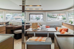 A modern interior with a dining area, seating, and a view through large windows. - Sun-Kissed Sailing Adventure in the Ionian Islands, Lefkada (Lefkada)