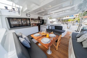 A boat's interior with a dining area, a kitchen, and seating. - Sun-Kissed Sailing Adventure in the Ionian Islands, Lefkada (Lefkada)