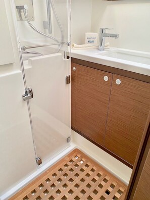 Ein Badezimmer mit Dusche, Waschbecken und Holzschränken.