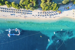 An aerial view of a beach with clear turquoise waters, a pier, and several boats. - Sun-Kissed Sailing Adventure in Sibenik, Croatia (Primošten)