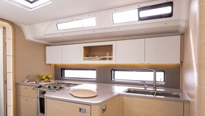 A compact kitchen with a stove, sink, and upper cabinets. - Dubrovnik Delight: A Sun-Kissed Sailing Experience (Komolac)