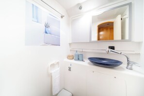 A bathroom with a white sink, a blue bowl sink, a towel rack, and a mirror.