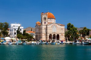Una iglesia costera con una cúpula destacada, junto a un puerto deportivo con barcos.