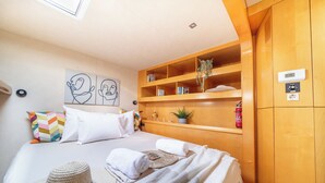Ein Schlafzimmer mit Bett, einem Holzschrank, einem Regal mit Büchern und einer Pflanze sowie einer Deckenleuchte.