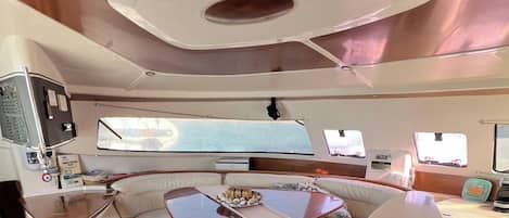 A boat interior with a control panel, seating, and a table.