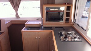 A compact kitchen with a built-in oven, a gas stove, and a sink. - Sun-Kissed Sailing: An Unforgettable Beach Experience in Istria, Croatia (Medulin)