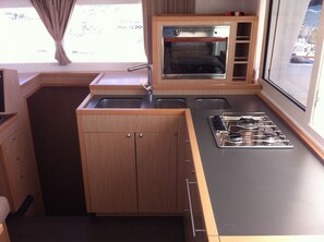 A compact kitchen with a built-in oven, a gas stove, and a sink. - Sun-Kissed Sailing: An Unforgettable Beach Experience in Istria, Croatia (Medulin)