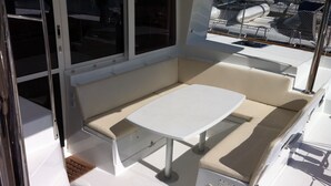 A sunlit interior with a white table and cushioned seating, large windows, and a view of boats outside. - Sun-Kissed Sailing: An Unforgettable Beach Experience in Istria, Croatia (Medulin)