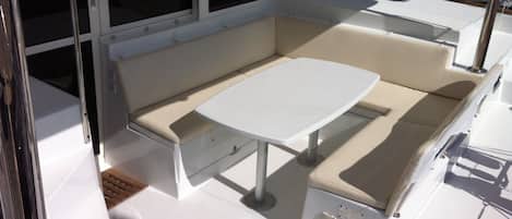 A sunlit interior with a table and cushioned seating area.