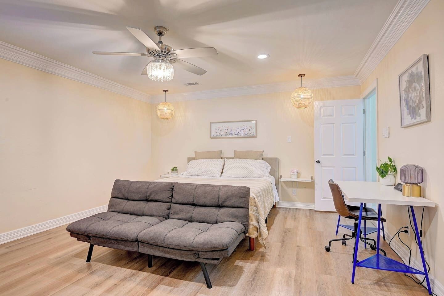 Une chambre à coucher comprenant un lit, un bureau, une chaise, un ventilateur de plafond et un luminaire fixé au mur.
