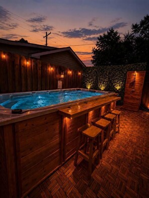 Un espacio tipo spa de madera con un jacuzzi y taburetes de bar.