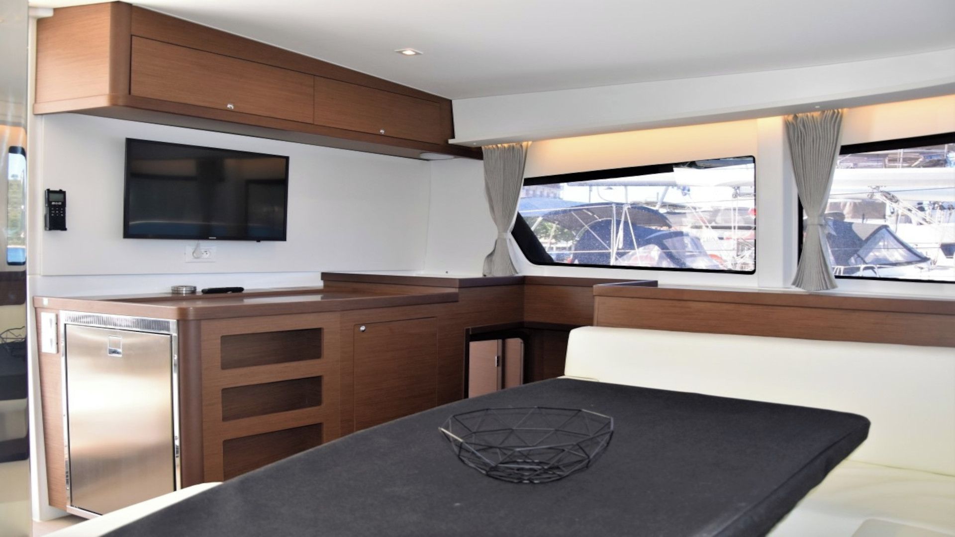 Una piccola cucina compatta con TV a schermo piatto, mobili in legno e una finestra che offre vista sugli edifici.