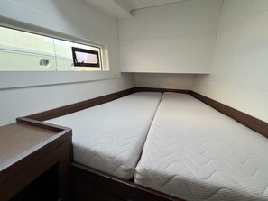 Une petite chambre avec un lit simple, une fenêtre, un bureau en bois et une tête de lit.