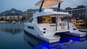 Un yacht blanc était amarré dans une marina, avec un pont couvert et une vue sur les bâtiments environnants.