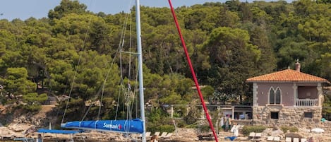 A sailboat with a blue cover and a stone building with a red roof in the background.