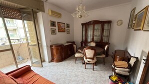 Un salon comprenant un canapé, une table à manger, des chaises, un buffet et un lustre.