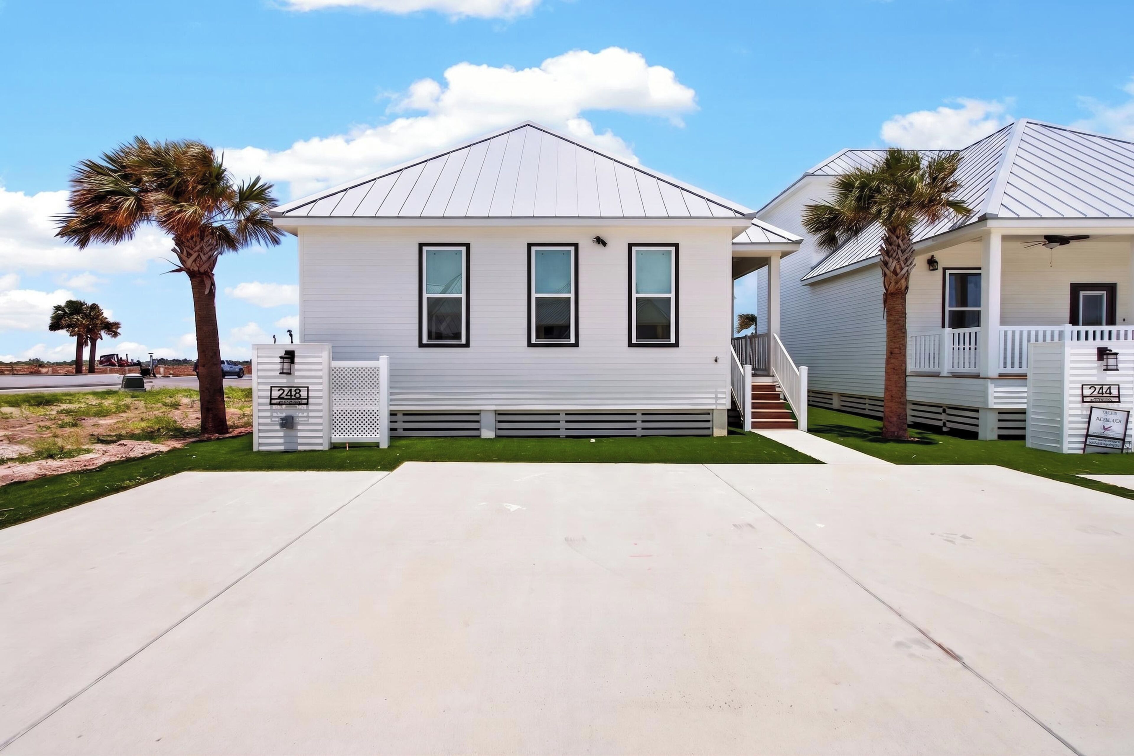 Une maison à deux étages, avec une façade blanche, un porche à l’avant et un garage.