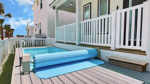 Un área de piscina con una plataforma flotante, muelle de madera y valla blanca.