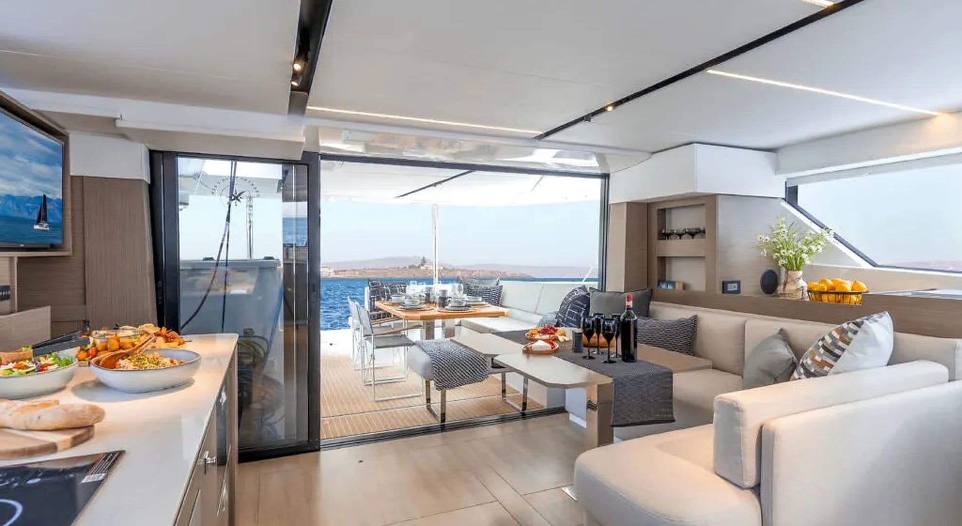 A yacht interior with a dining area, seating, and a view of the sea.