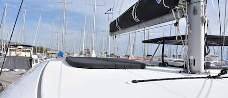 A marina with multiple sailboats docked, a covered area with a logo, and a white boat with a grey deck.
