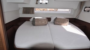 Un lit avec deux oreillers, une fenêtre avec des rideaux et une vue sur l’extérieur.