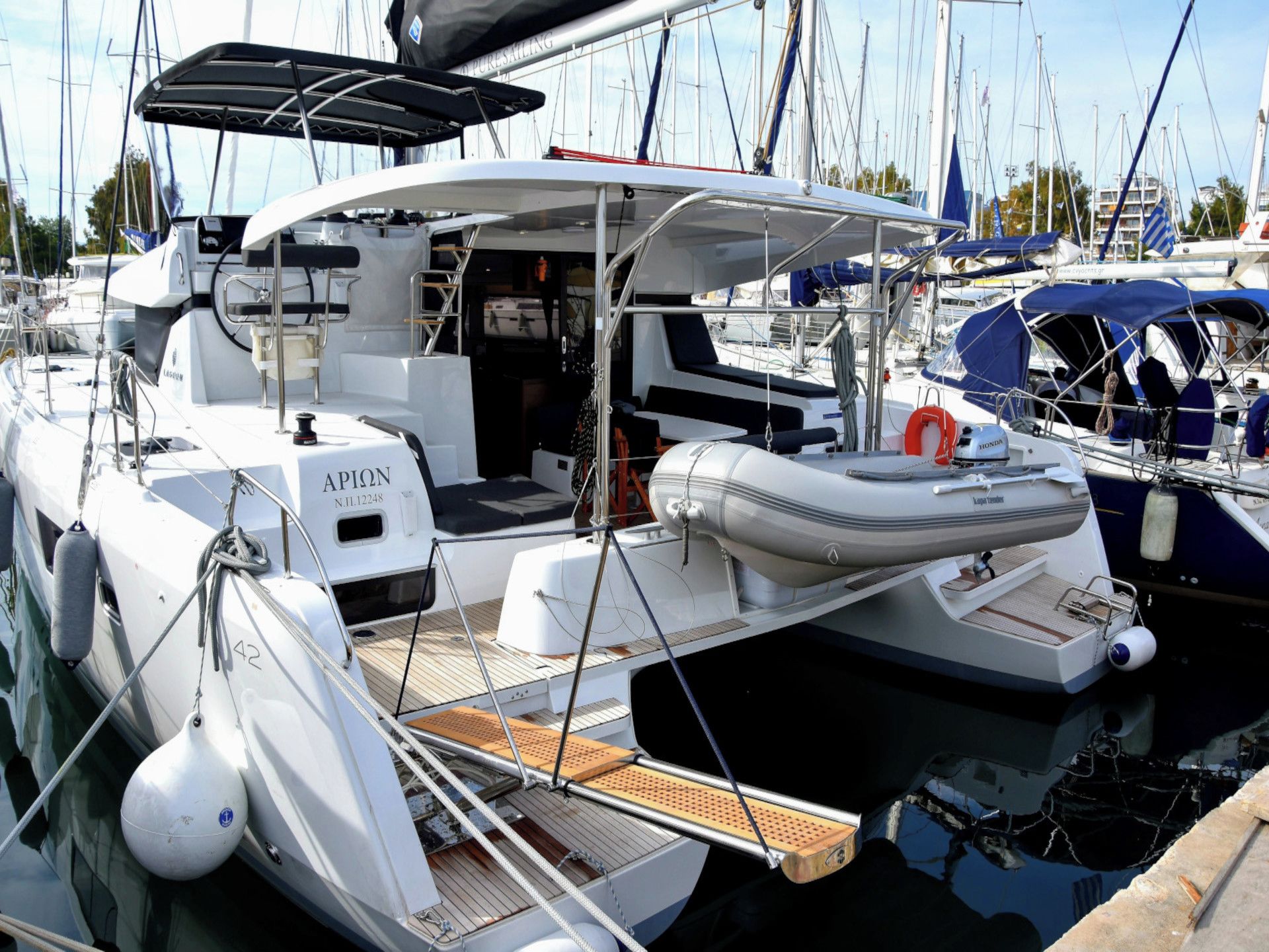 A marina with a white yacht featuring a covered deck, a seating area, and a lifebuoy.
