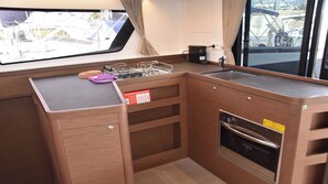 A compact kitchen with a sink, stove, and storage drawers. - Sun-Kissed Sailing Adventure in Islas Esporadas (Skiathos)