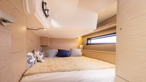 A compact, well-lit interior with a bed, storage cabinets, and a window providing natural light.