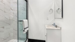 A modern bathroom with a glass shower enclosure, a white sink, and a mirror above the sink.