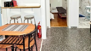 Ein Zimmer mit Esstisch, Stühlen, einem Feuerlöscher, einem Bett und einem Badezimmer mit Marmorwand.