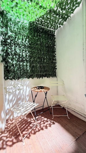 Ein Zimmer mit Holzboden, einem runden Tisch mit Stühlen und einer grünen Wand voller Pflanzen.