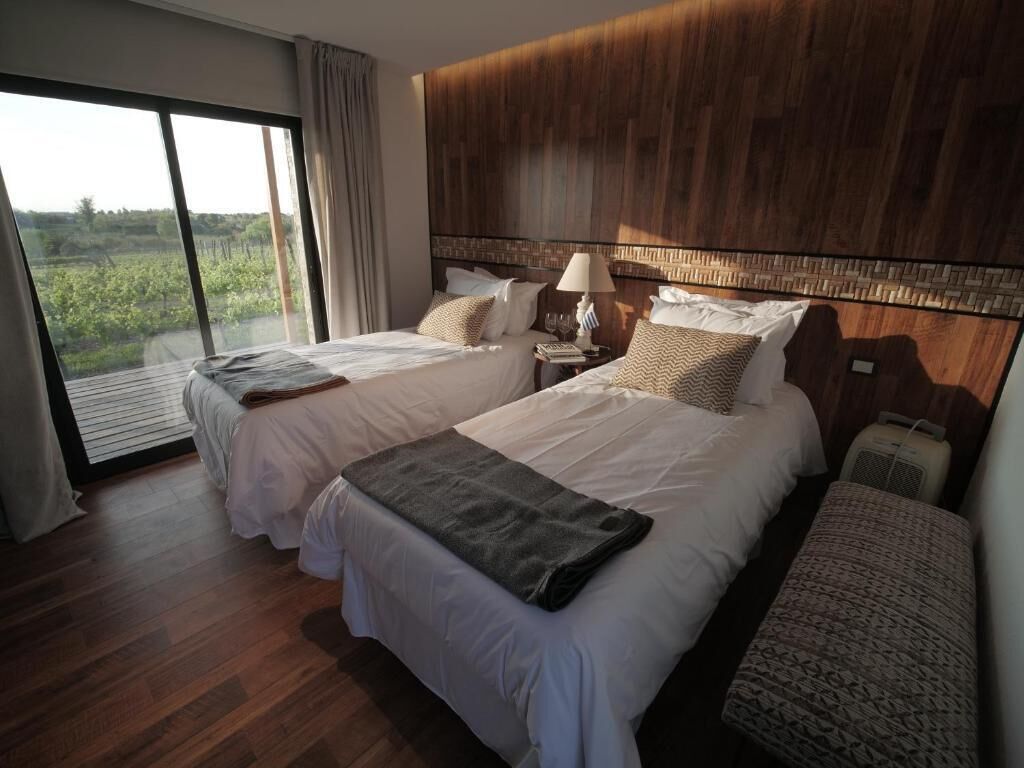 Habitación de hotel con dos camas, un ventanal grande y vistas a la vegetación.