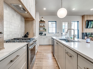 Een moderne keuken met witte kasten, een centraal eiland en een groot raam.
