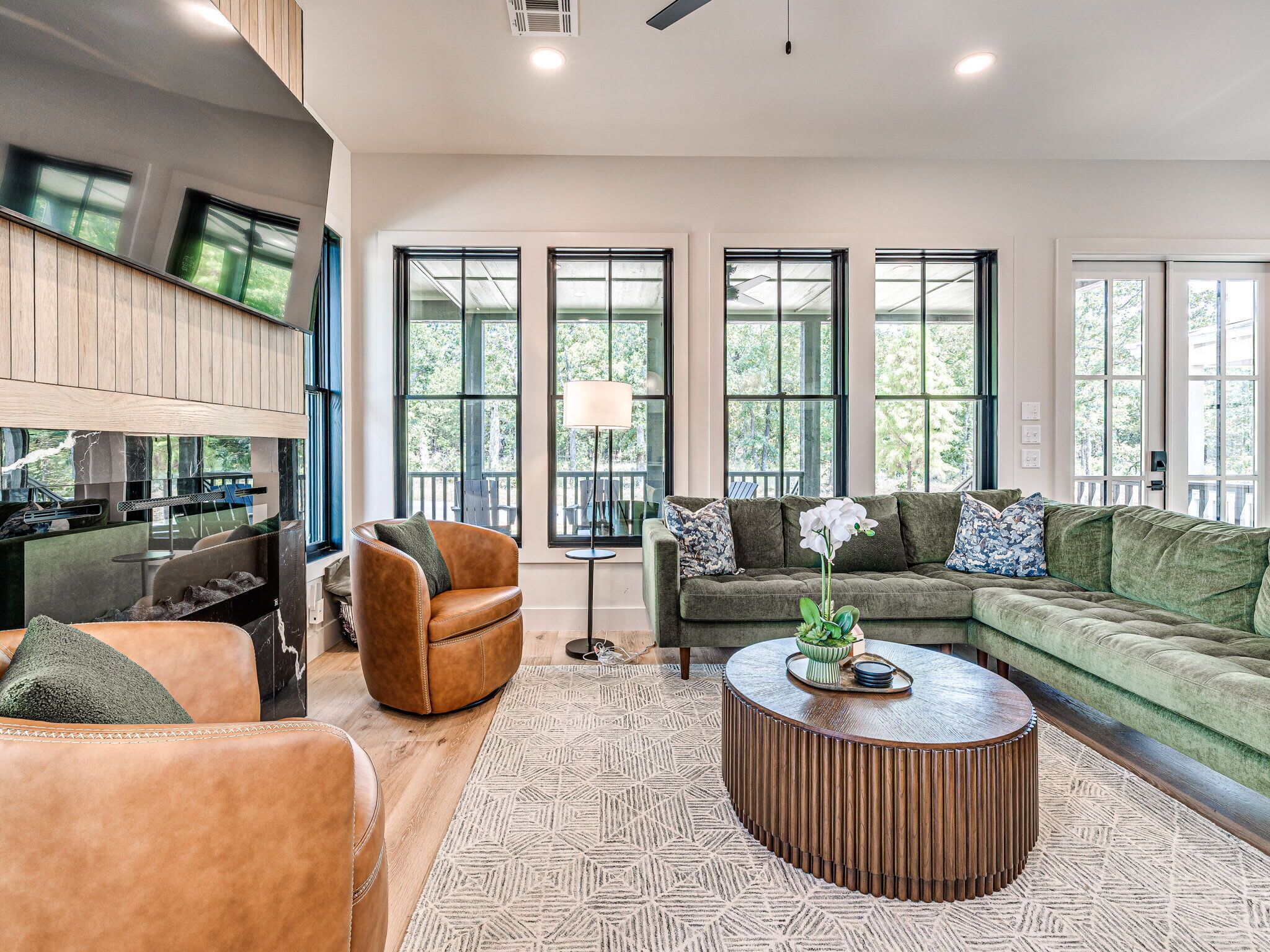 A modern living room with a leather sofa, a green sectional, and a round coffee table.