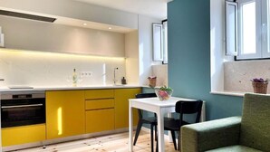 Una cocina moderna con armarios amarillos, una mesa de comedor blanca y un sofá verde.