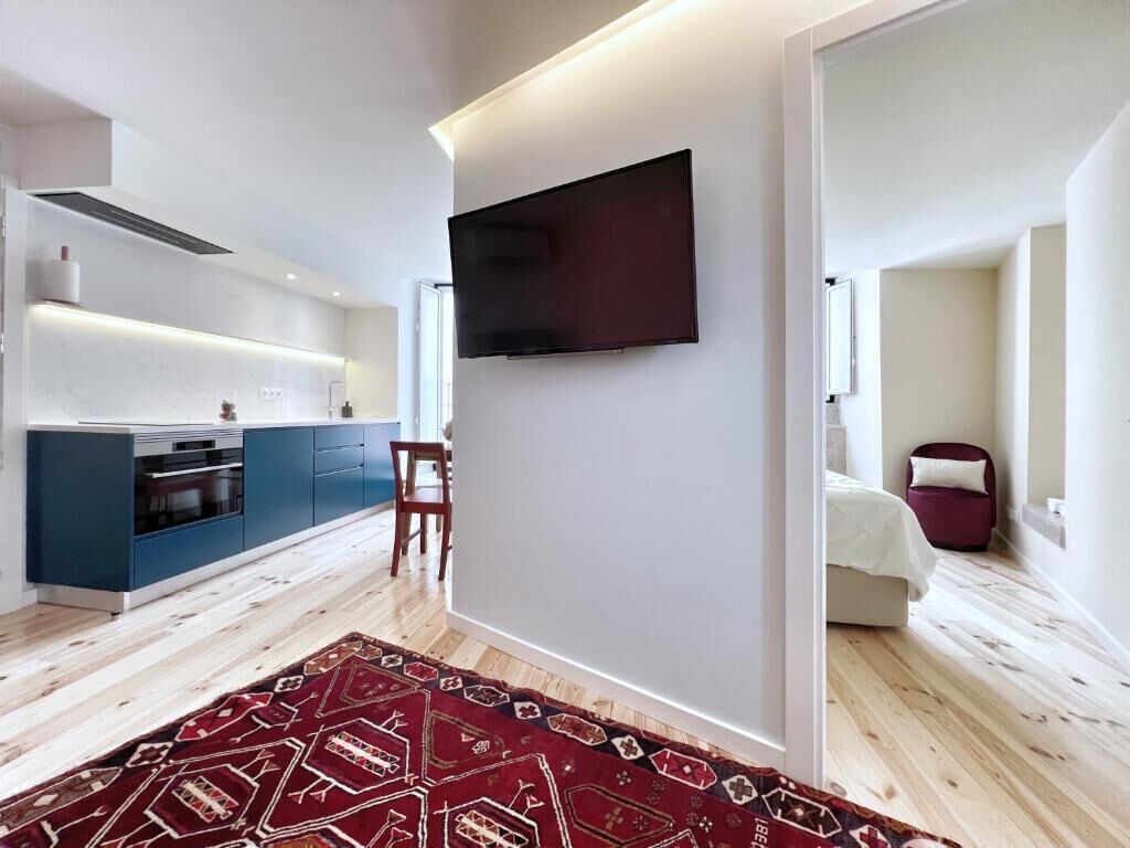 Ein modernes Interieur mit einer Küche, einem Flachbildfernseher und einem gemusterten Teppich.