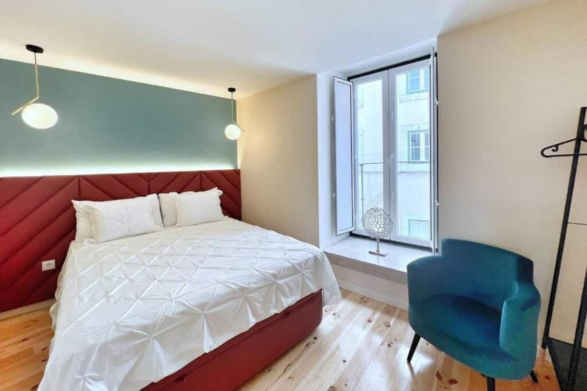 Un dormitorio con una cama, una ventana, una silla y una lámpara de pie.
