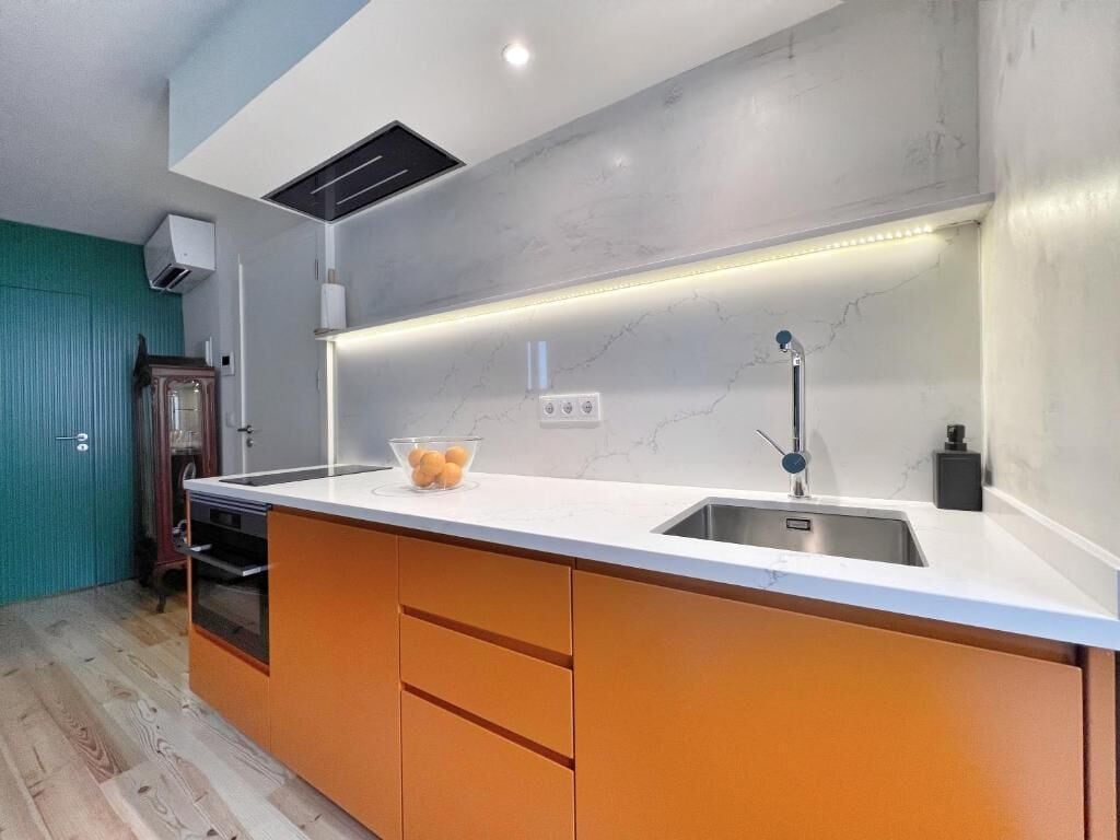 Eine moderne Küche mit einer großen Kochinsel, einem eingebauten Backofen und einer Marmor-Spritzschutzwand.