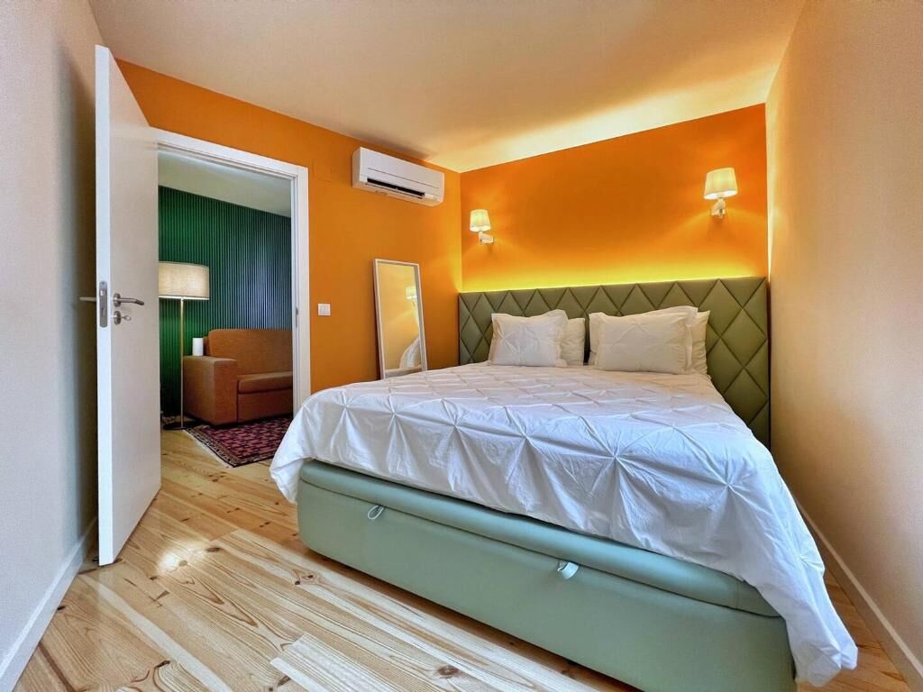 Et hotelværelse med en seng, et grønt sengegavl, en fastgjort aircondition og en lampe.