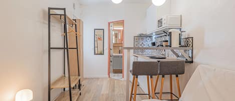 A modern kitchen with a dining area, wooden flooring, and pendant lighting.