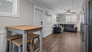 Ett modernt kök med ett inbyggt kylskåp, ett matbord med bänkar, en grå soffa och en takfläkt.