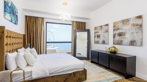 Et moderne hotelværelse med en stor seng, et mørkt konsolbord, et stort spejl og abstrakt vægkunst.